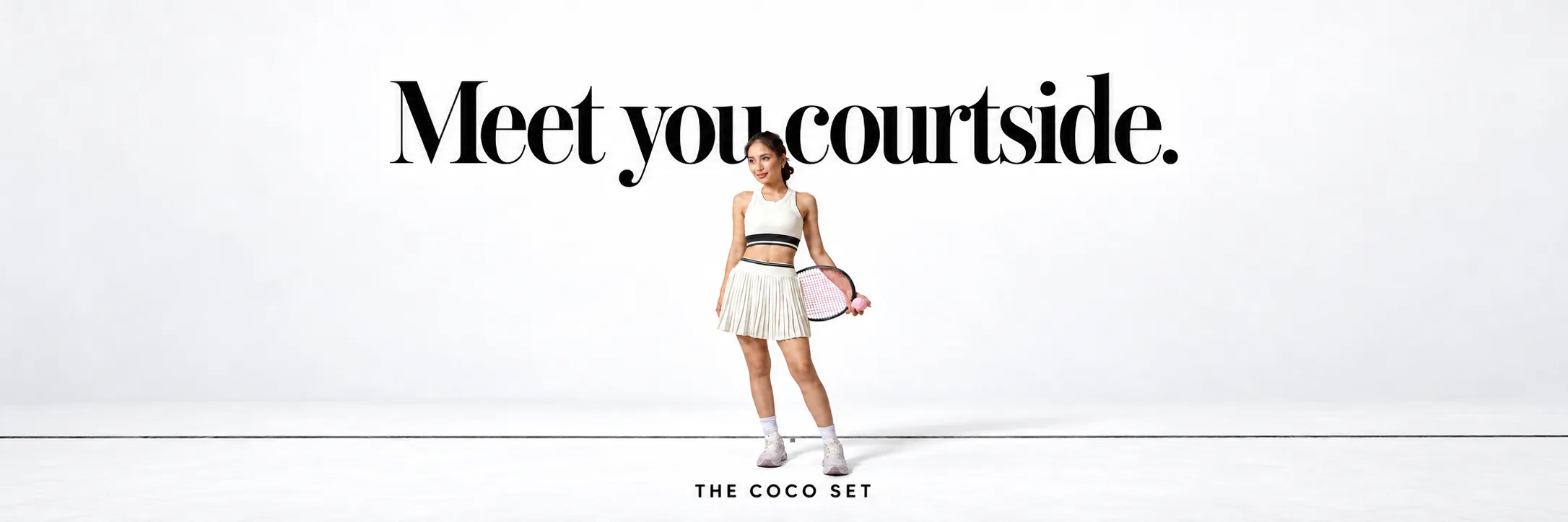 Meet you courtside. The Coco set with a tennis racket on a plain studio backdrop.